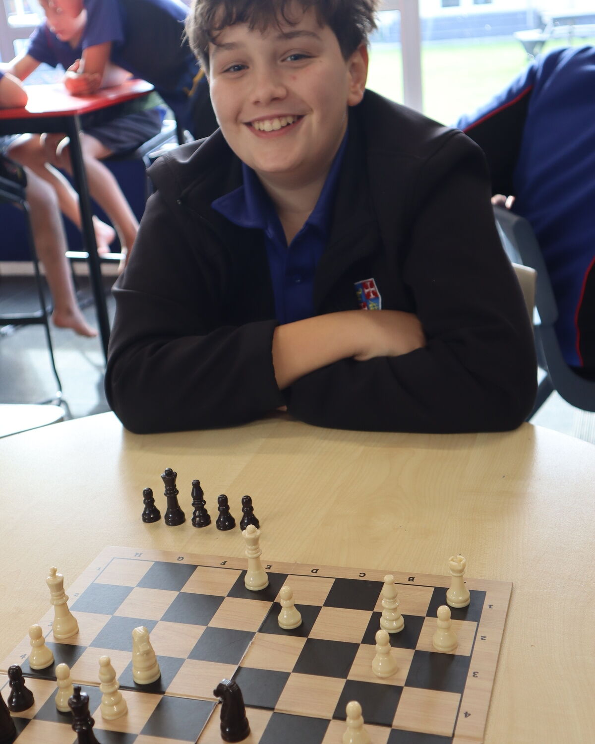 Smiling Maeroa Intermediate student sitting at a table playing chess.