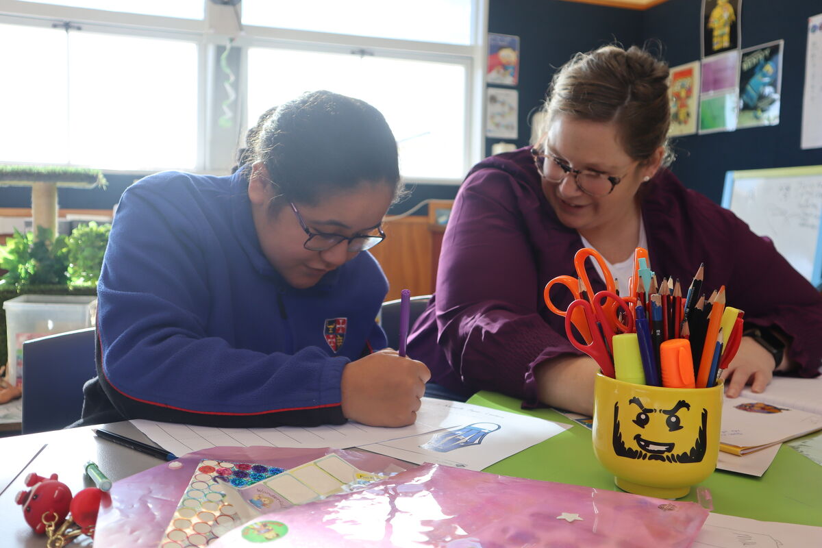 Student working on a classroom project with support from a teacher.