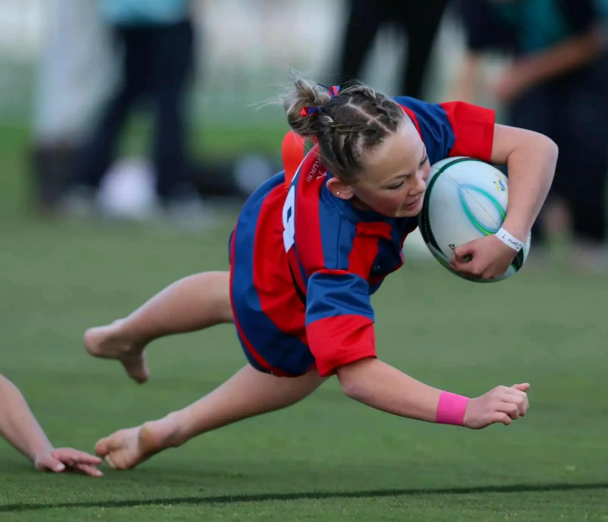 Student at Maeroa Intermediate diving with a rugby ball in their arm.